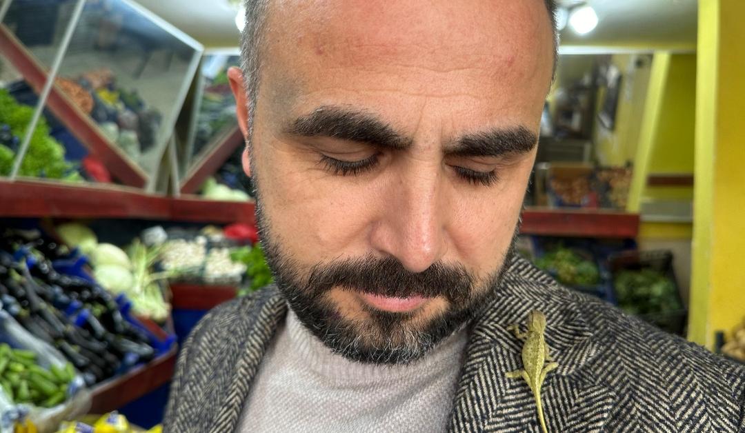 Ozkan Helvacioglu stands in a grocery store in Tokat, Turkiye with a chameleon he named 'Patron' on his left shoulder