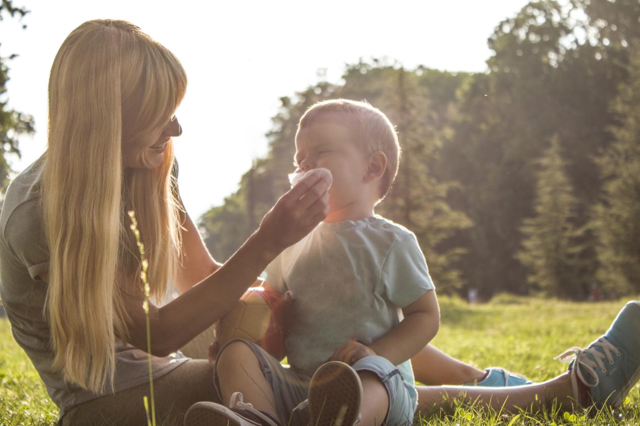 A smiling mother wipes her child's face with a single-use homemade baby wipes in the park.