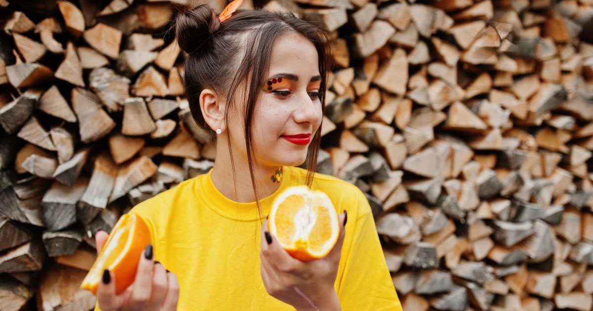 A woman holding pieces of orange in a garden. (Representative Cover Image Source: Freepik | AS Photo family)