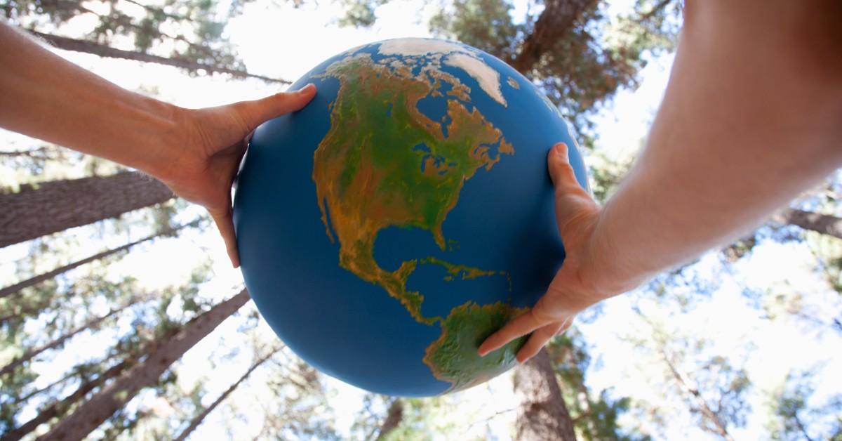 A globe being held in the center of some trees