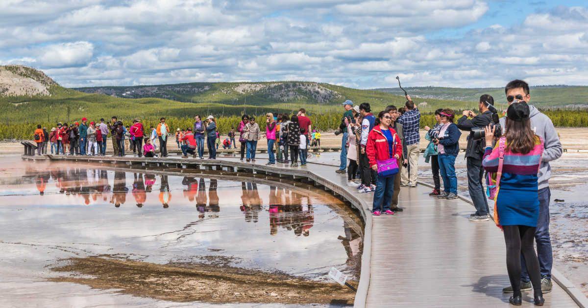 Tourists watching a geyser at Yellowstone National Park. (Representative Cover Image Source: Getty Images | ablokhin)