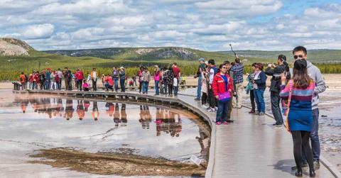 Tourists watching a geyser at Yellowstone National Park. (Representative Cover Image Source: Getty Images | ablokhin)