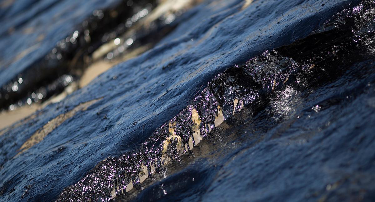 Oil spill on beach rocks