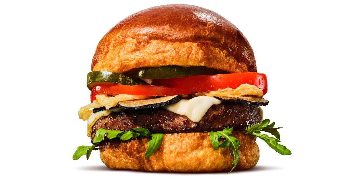 A hamburger made with an Impossible Indulgent Burger patty, lettuce, tomato, mayo, and more.