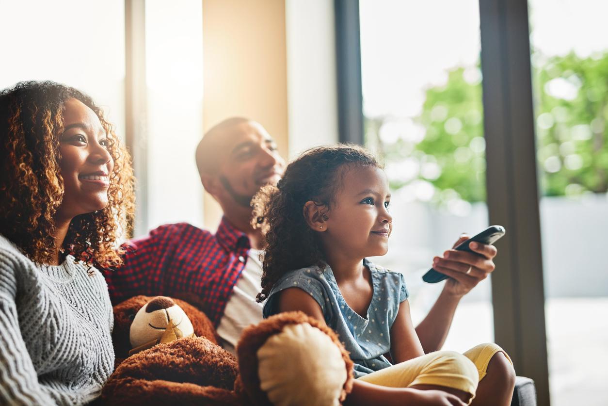 Parents watching tv with child