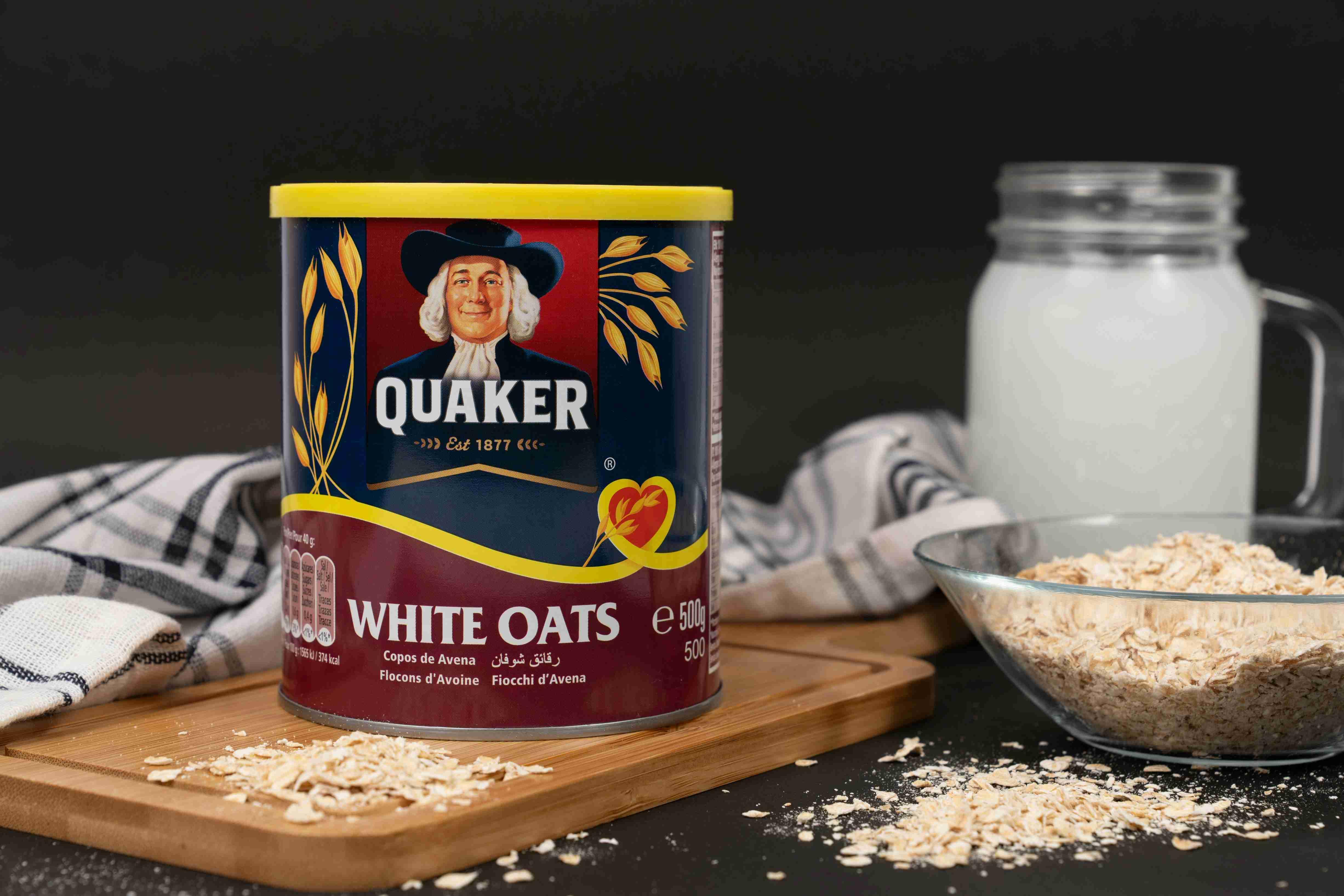 A container of raw white oats is pictured beside a glass bowl of oats.