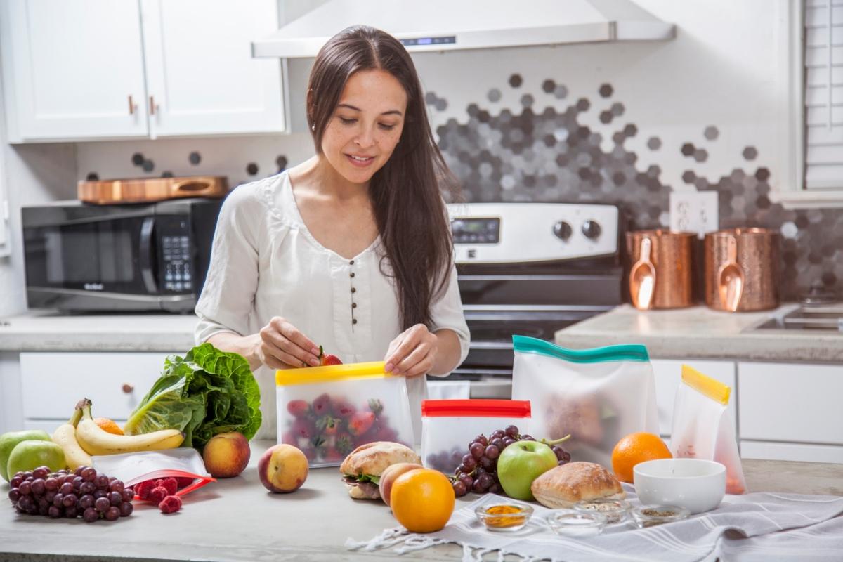 brunette woman putting fruit into zip-top bags