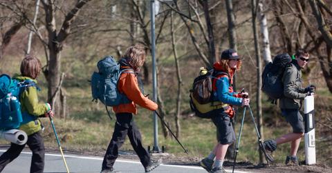A group of teenagers crossing a road with hiking gear