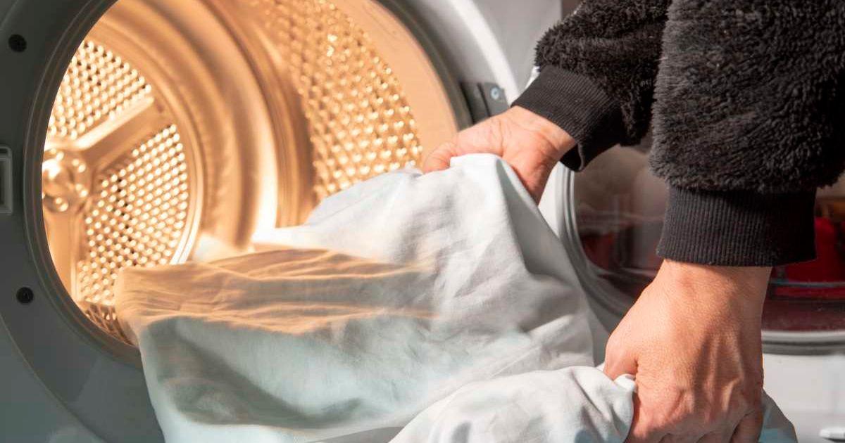 An individual loading a bed sheet into the tumble dryer. (Representative Cover Image Source: Getty Images | Eleonora Galli)