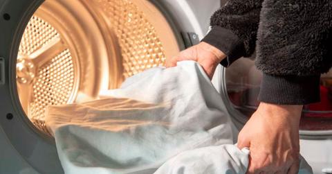 An individual loading a bed sheet into the tumble dryer. (Representative Cover Image Source: Getty Images | Eleonora Galli)