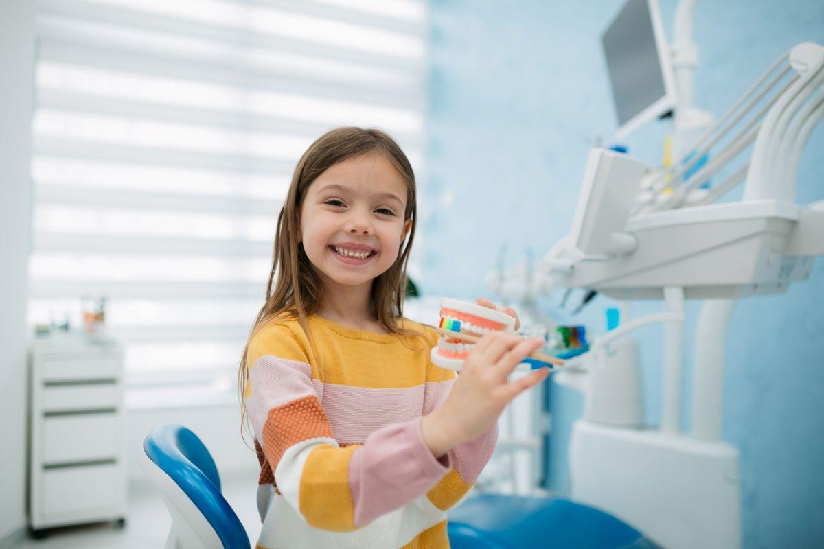 Little girl brushing teeth at the dentist