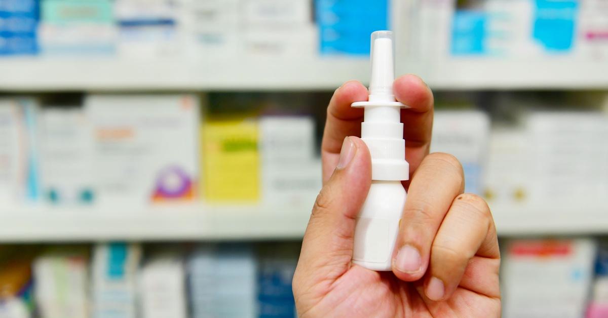 Photograph of person holding nasal spray in hand.