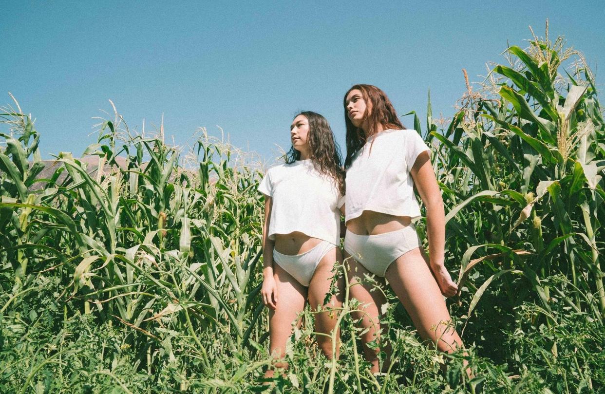 Two models wear white KENT underwear and T-shirts in a field