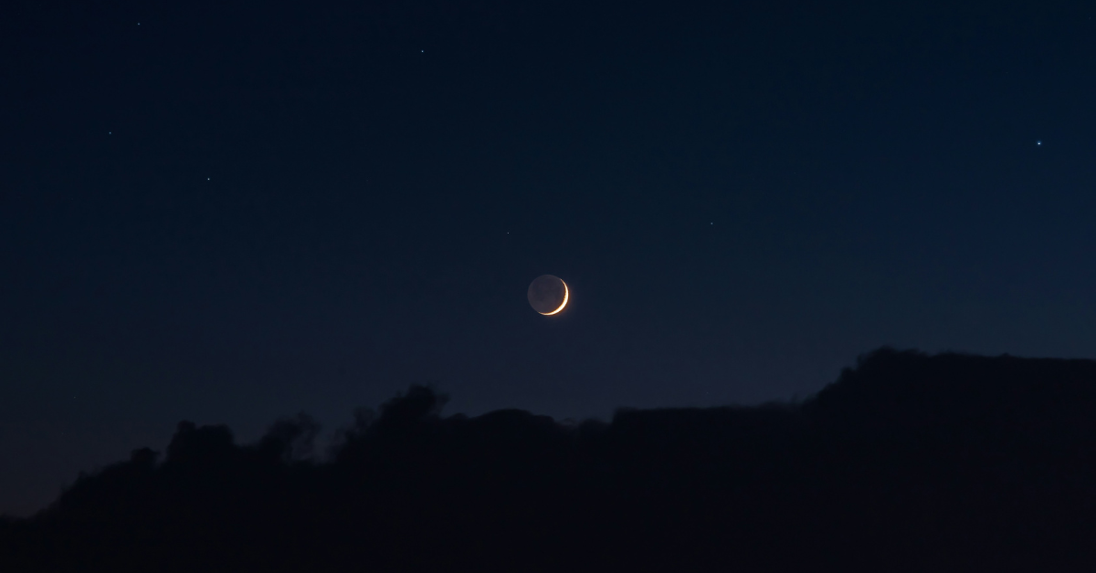 Photograph of a lunar eclipse over a mountain at night. 