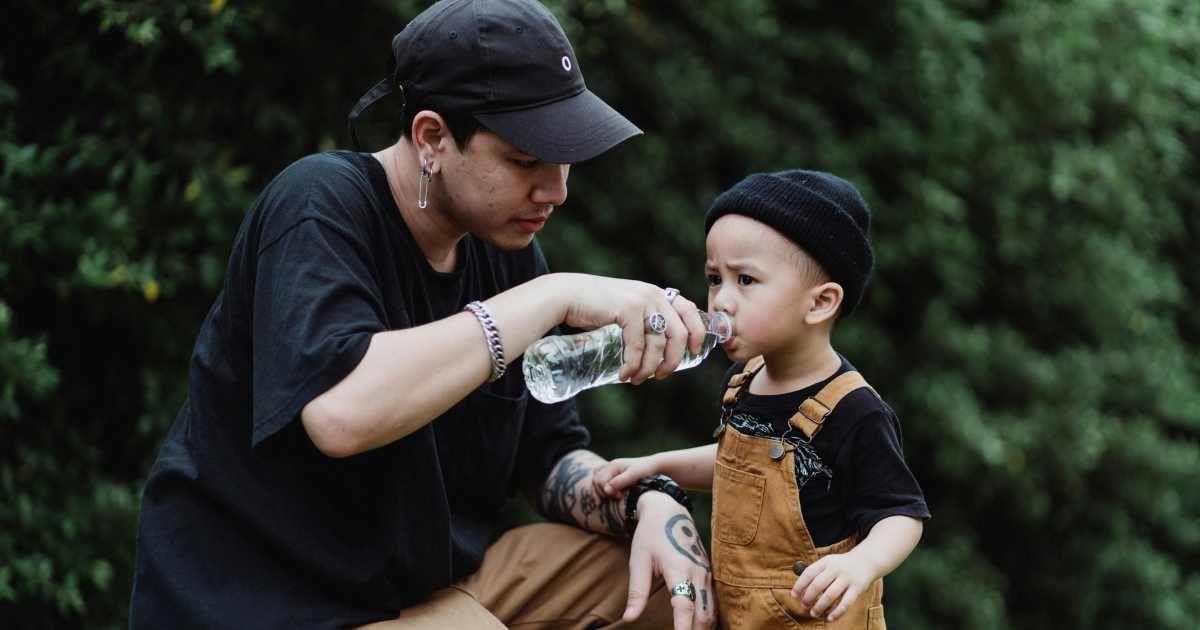 A little boy is being fed water from a plastic water bottle. (Representative Cover Image Source: Pexels | Ketut Subiyanto)