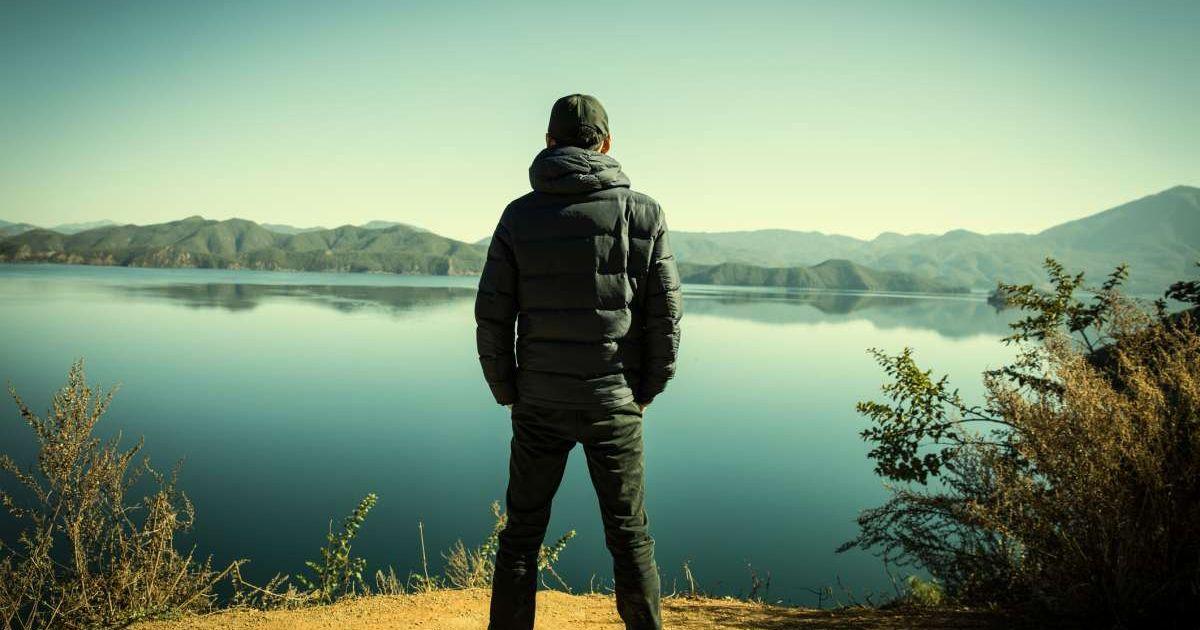 A man standing by a lake surrounded by clusters of bushes and plants. (Representative Cover Image Source: Getty Images | Linghe Zhao)