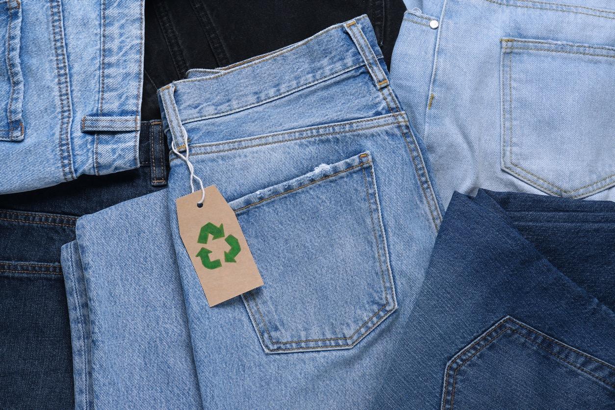 Light blue jeans with a brown recycling tag hanging on the belt loop.