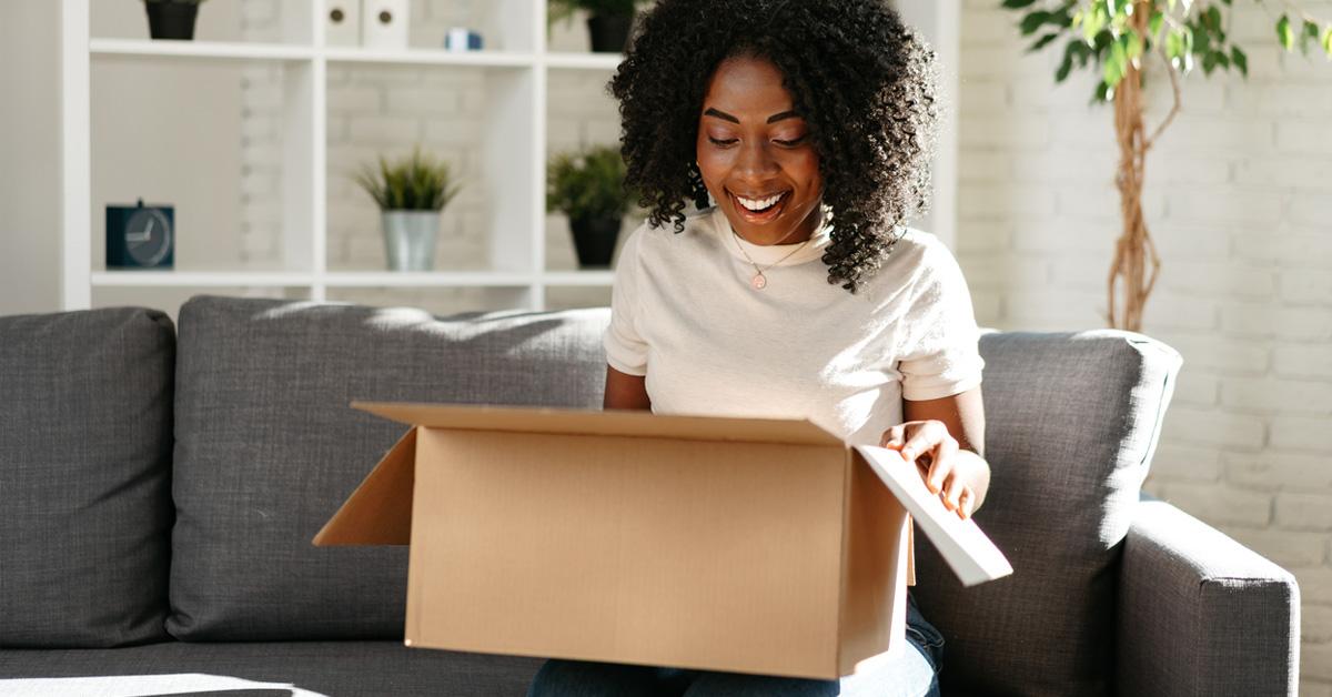 Woman unpacking moving boxes on a couch.