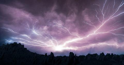 A lightning bolt streaks out across the sky above some rocks