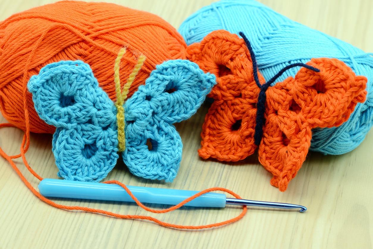 Two crochet butterflies, one orange and one blue.