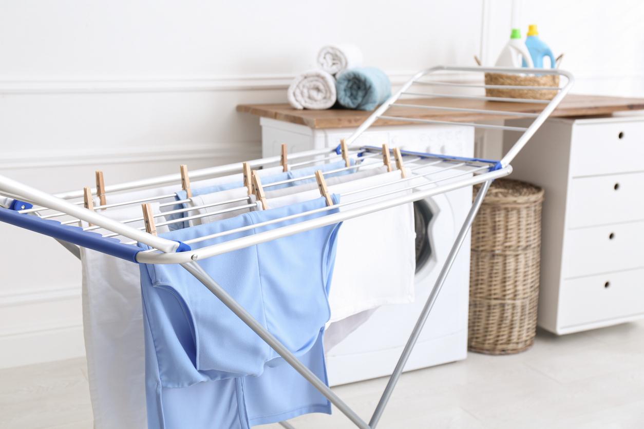 A few blue and white clothing pieces pinned on an indoor drying rack in a laundry room.