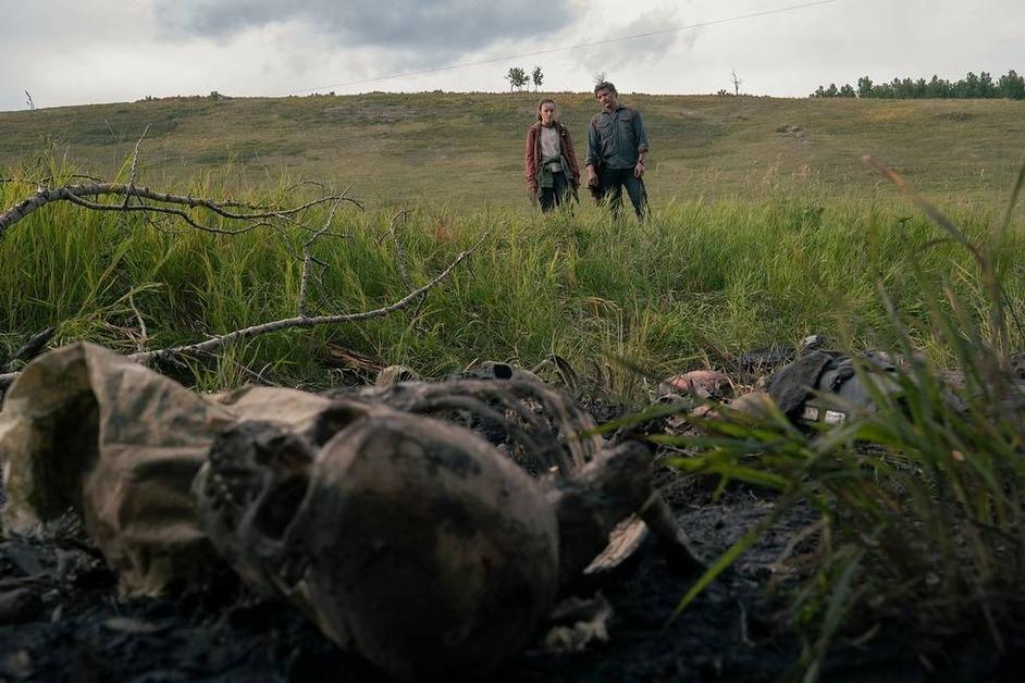 Bella Ramsey and Pedro Pascal looking at bones from a distance in 'The Last of Us.'