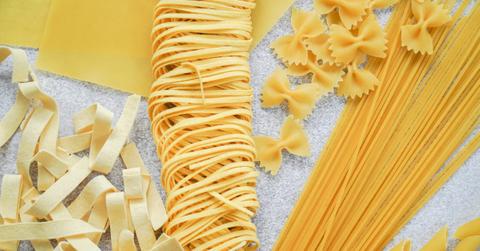 A collection of raw pasta noodles, including bow tie and spaghetti