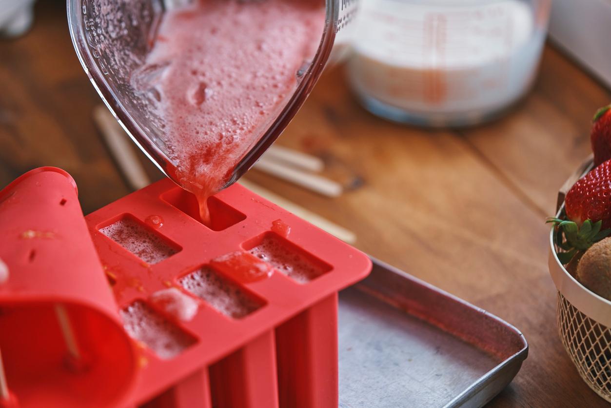 Person pouring pureed watermelon from a blender into a rubber popsicle mold.