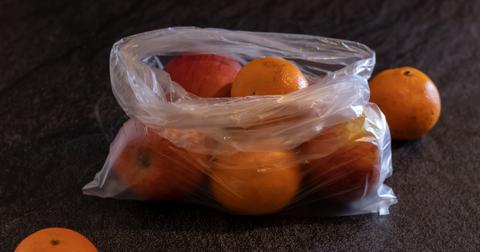 Plastic bag full of oranges and apples.