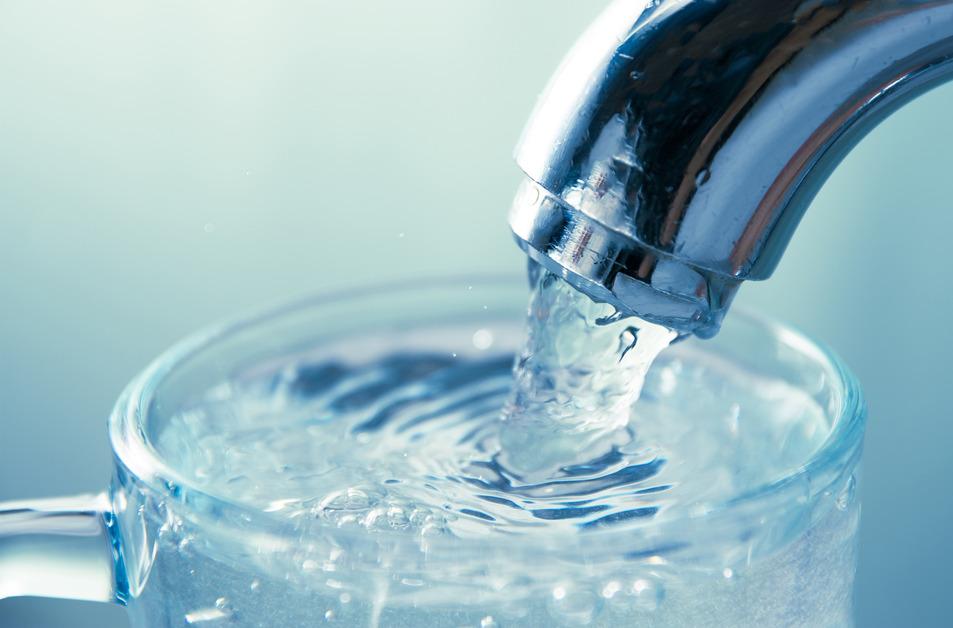 A close-up photo of a water faucet filling up a glass. 