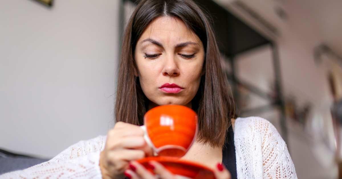 A woman is looking at her coffee mug with a doubtful expression on her face. (Representative Cover Image Source: Getty Images | Vladimir Timotijevic)
