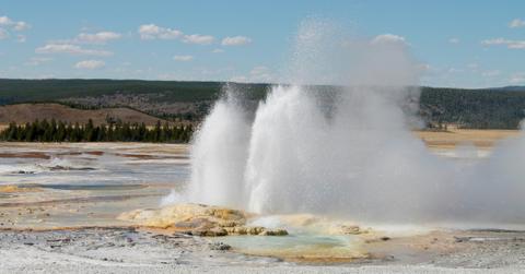 A geyser in Yellowstone erupts in the distance
