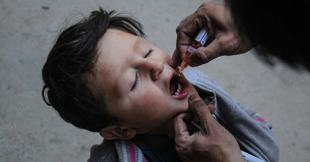 A boy opens his mouth as a healthcare worker gives him the polio vaccine 