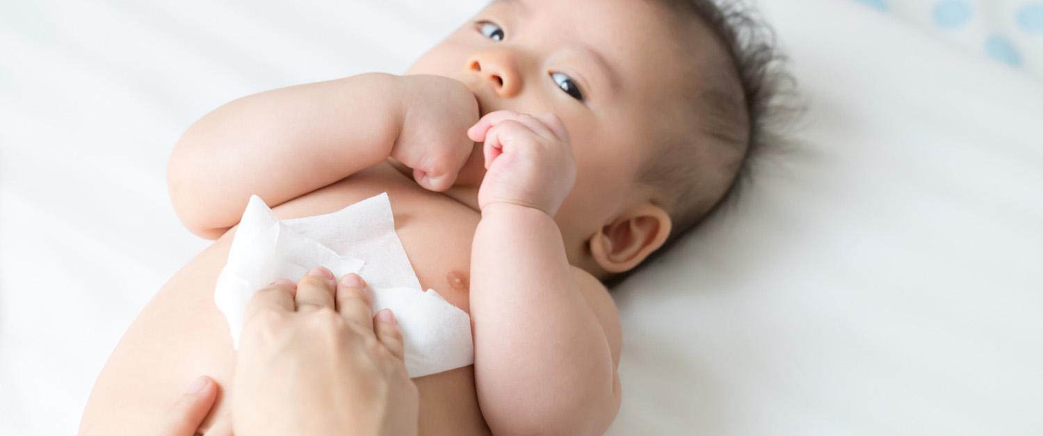 parent using a baby wipe on a baby