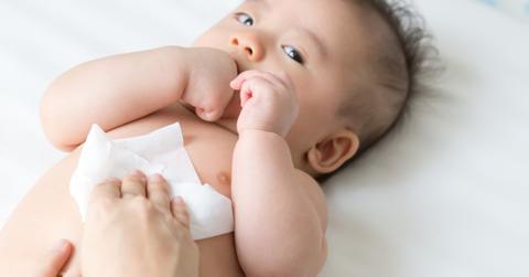 parent using a baby wipe on a baby