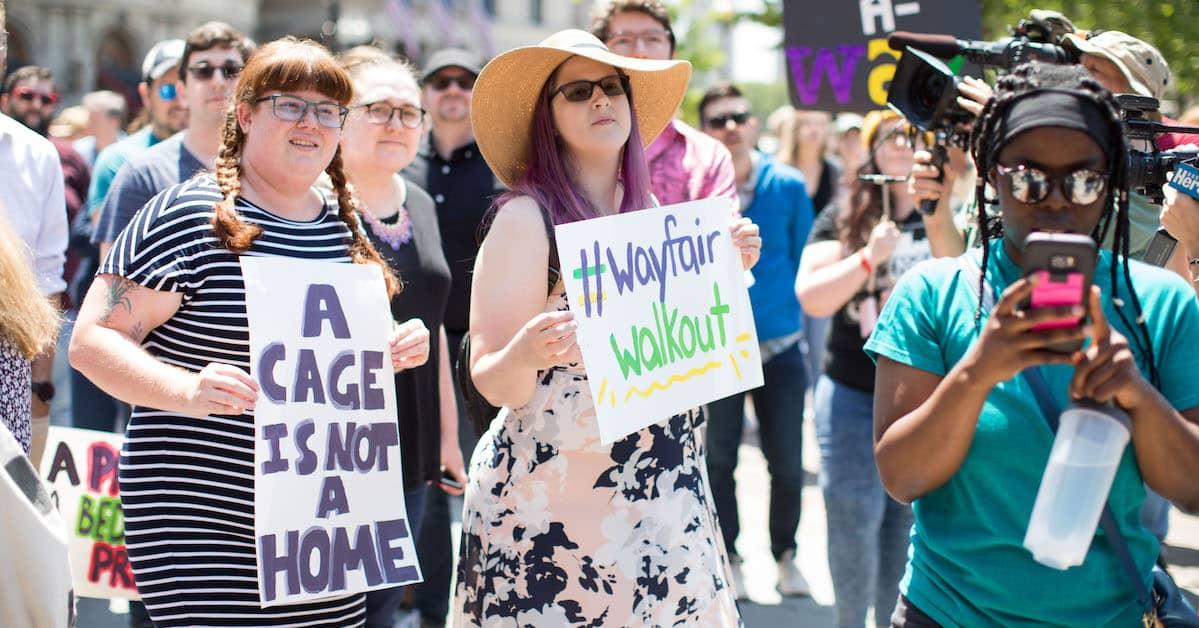 Large group of protestors carrying placards saying "a cage is not a home" and "Wayfair walkout"