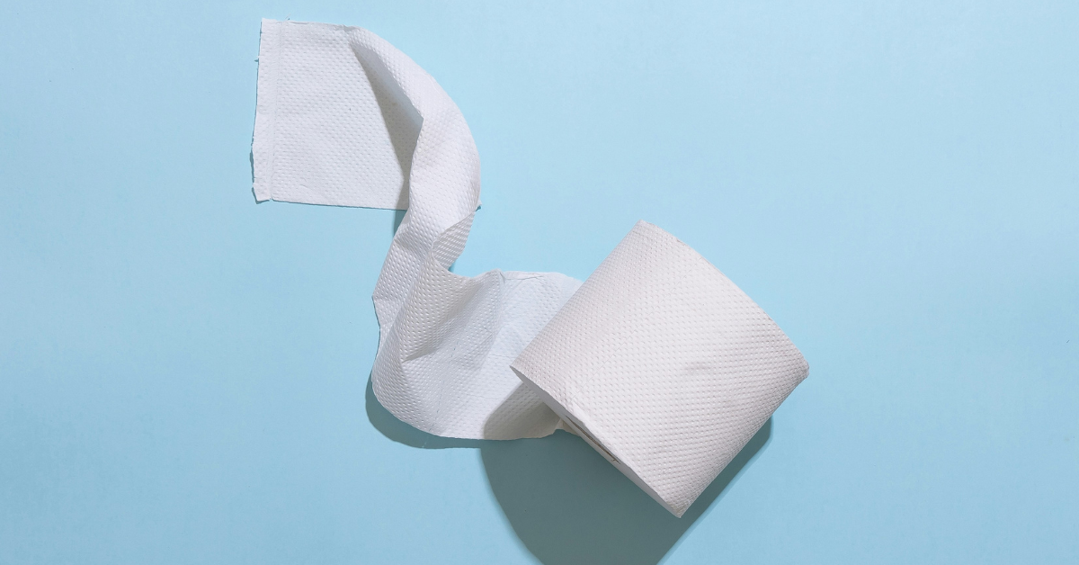 A partial unspooled roll of toilet paper sits against a blue background 