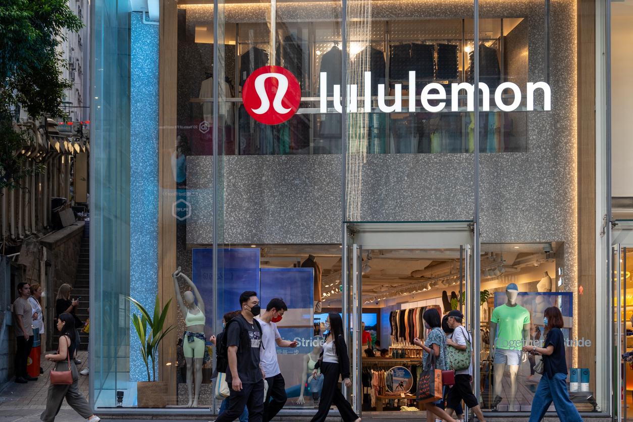 People walking outside the front of a large Lululemon store.