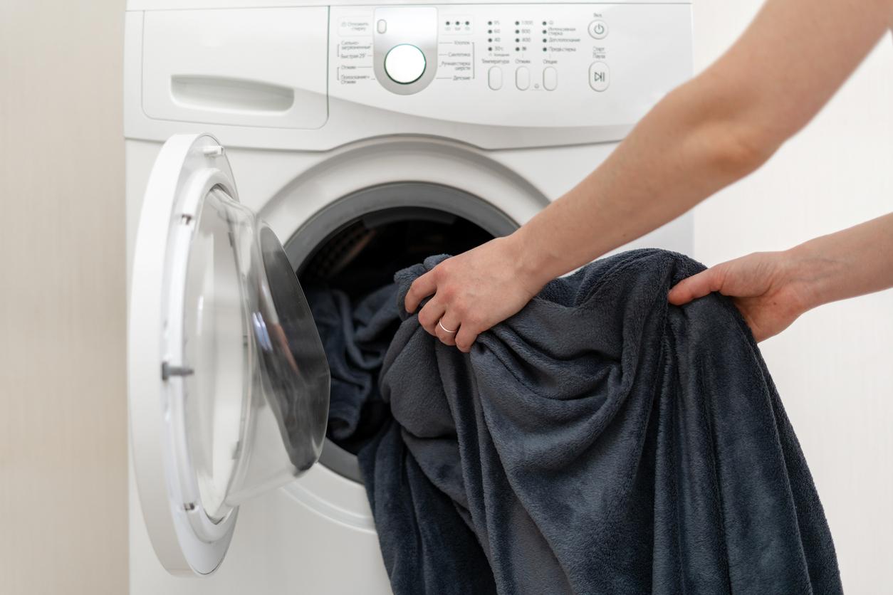 Person removing a black blanket from the dryer.