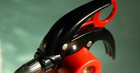 Closeup of fire extinguisher against a green background.