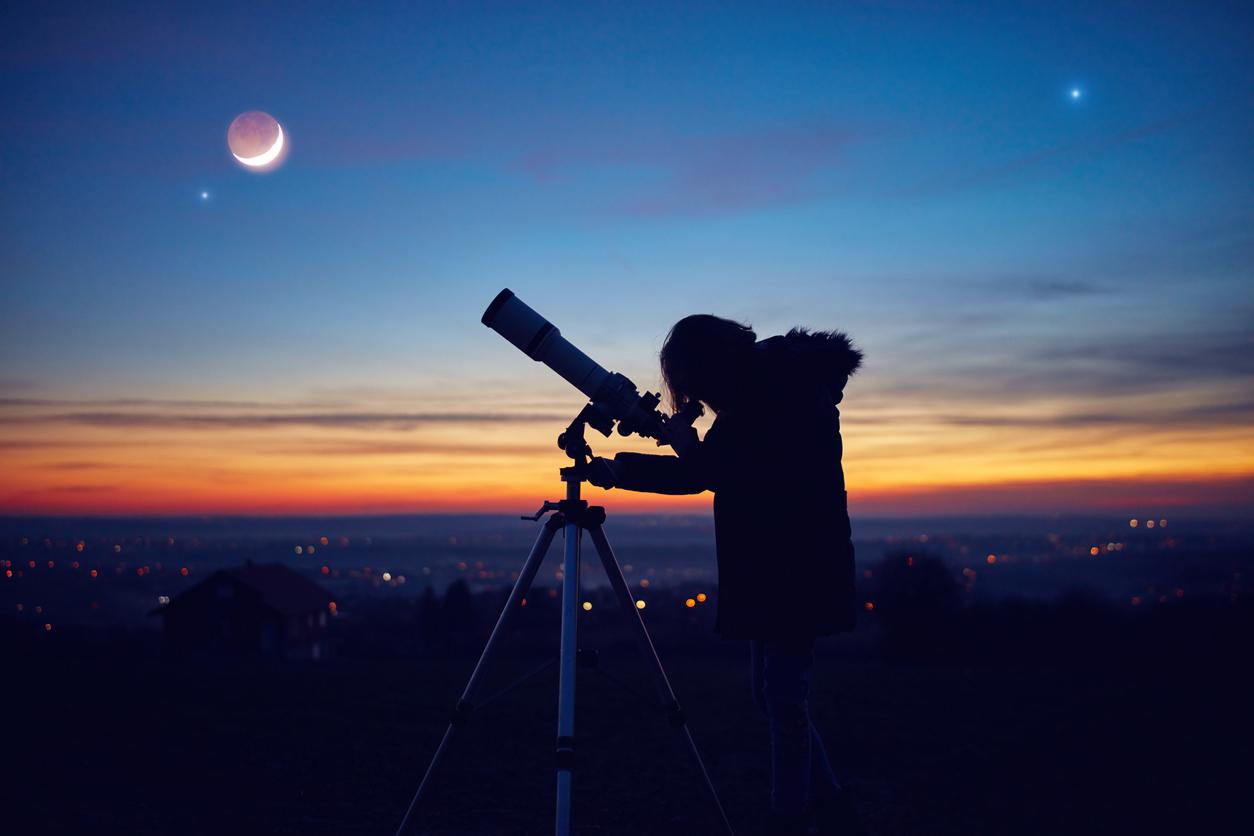 A child observes the night sky through a telescope.