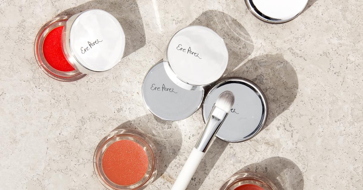 A few pots of Ere Perez makeup products and a brush on a counter