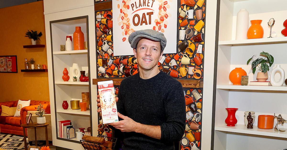 Jason Mraz smiles and holds up a Planet Oat Barista Lovers carton at a Planet Oat pop-up event at Chelsea Market in New York City, on Jan. 25, 2024.