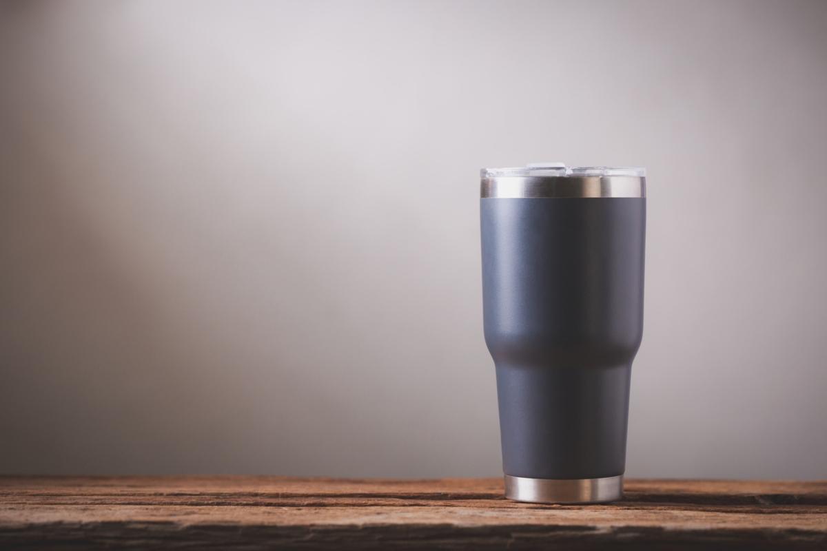 Dark stainless steel tumbler on a wooden table.