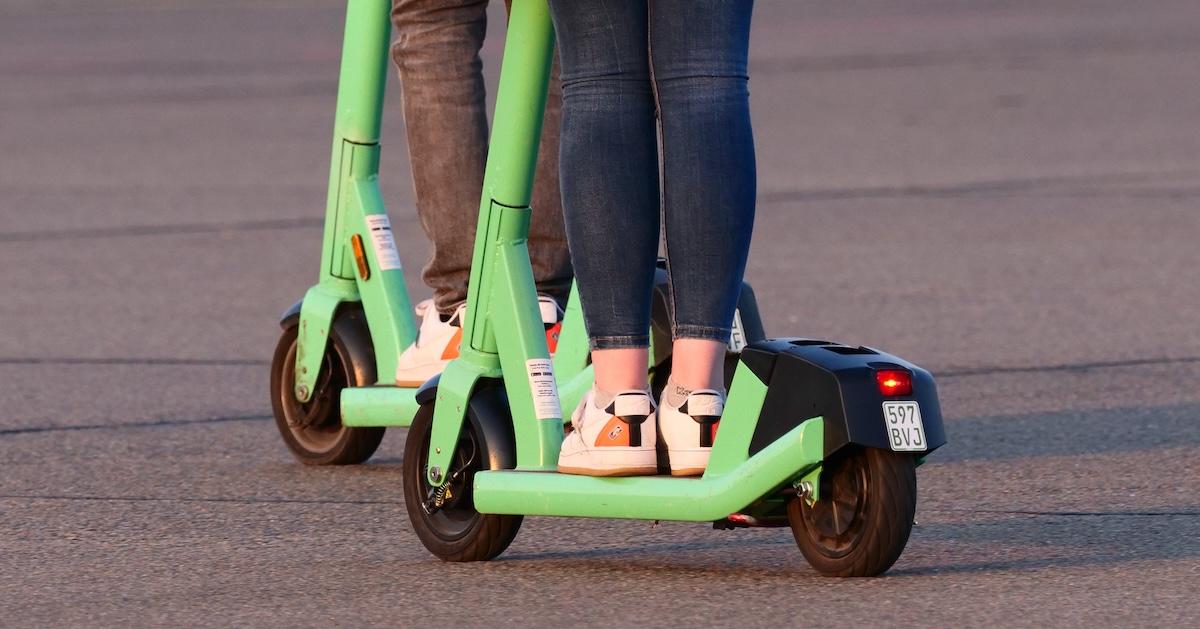 Closeup of legs of two young women ride electric scooters on Tempelhofer Feld in Berlin.