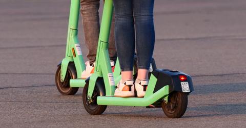 Closeup of legs of two young women ride electric scooters on Tempelhofer Feld in Berlin.