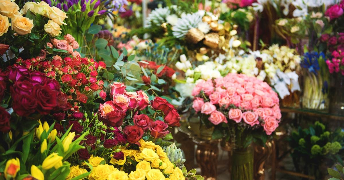 Close-up photograph inside a flower shop of flowers in vases and on shelves. 