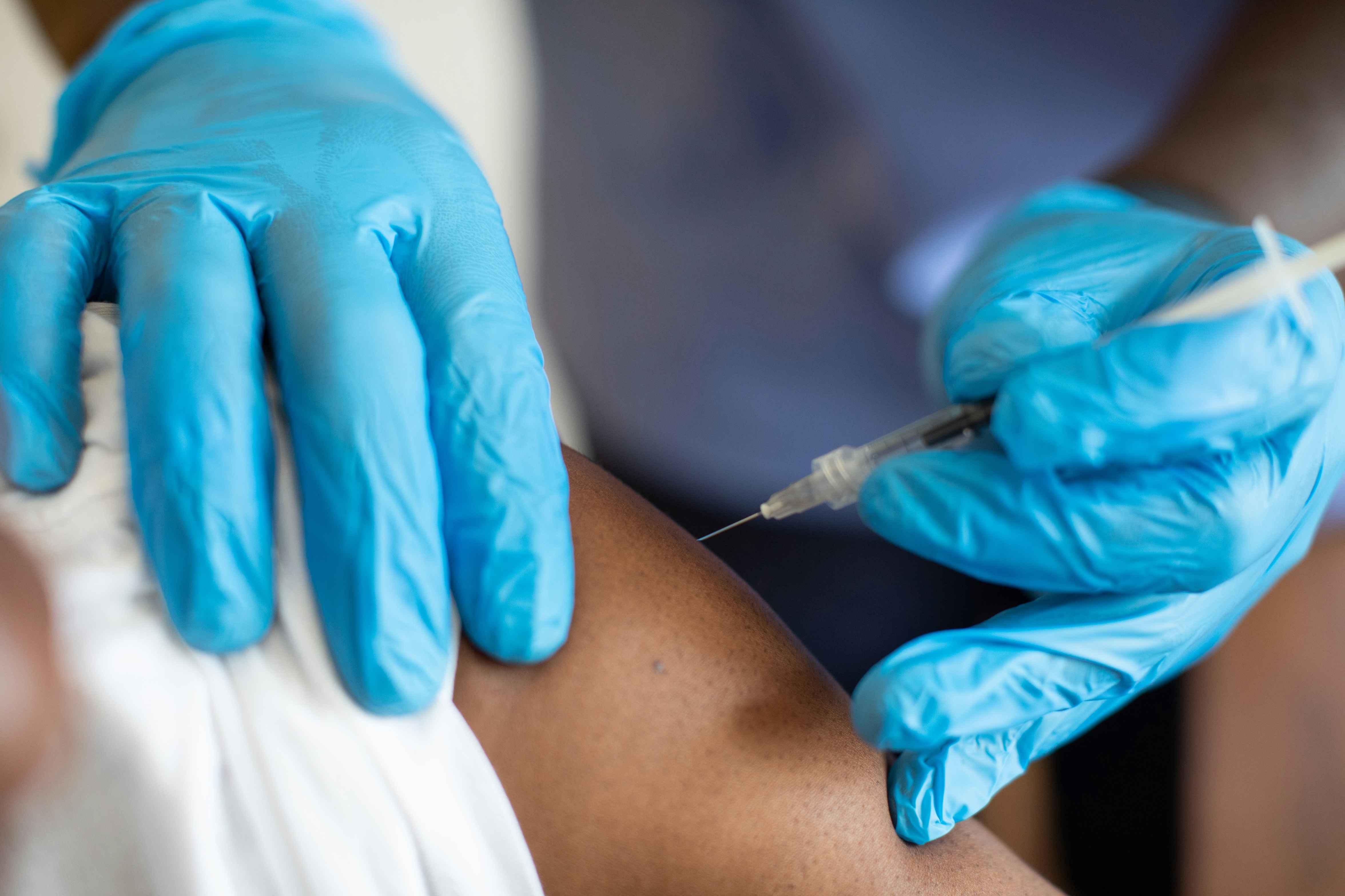 A doctor in a hospital administers a vaccine to a patient's upper arm.