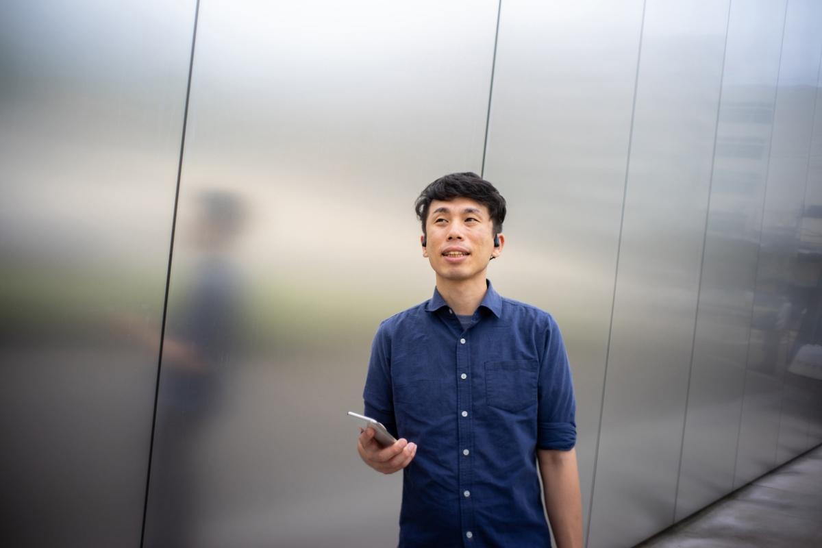 young Asian man in blue shirt with bone conduction headphones