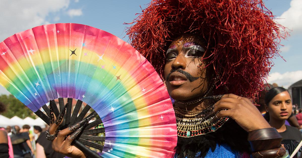 Rudy Jeevanjee from Stonewall charity holds a designed rainbow hand fan to raise money at the U.K. Black Pride in Haggerston Park in London on July 7, 2019. 